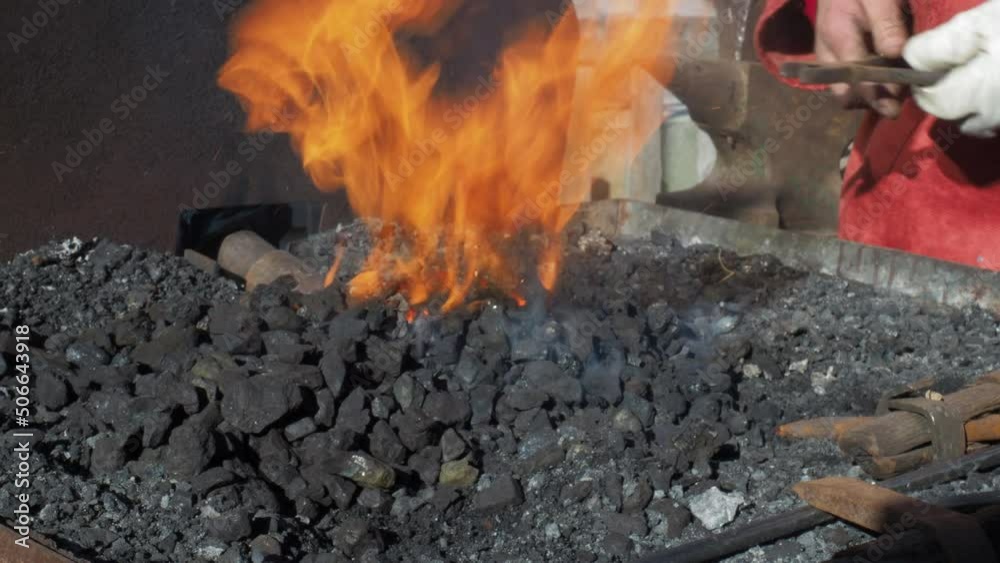 Closeup of blacksmith heating up metal hook wearing protective gloves, day Closeup of blacksmith heating up metal hook wearing protective gloves, day