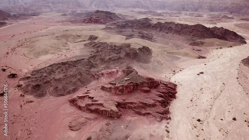 High Spiral hill in the barren rocky and hilly landscape of the Red Canyon in Timna Park in the Negev Desert in southern Israel. Backwards drone dolly shot photo