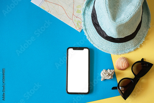 Travel kit with hat, travel card, smartphone and sunglasses on a blue background.Travel flat lay