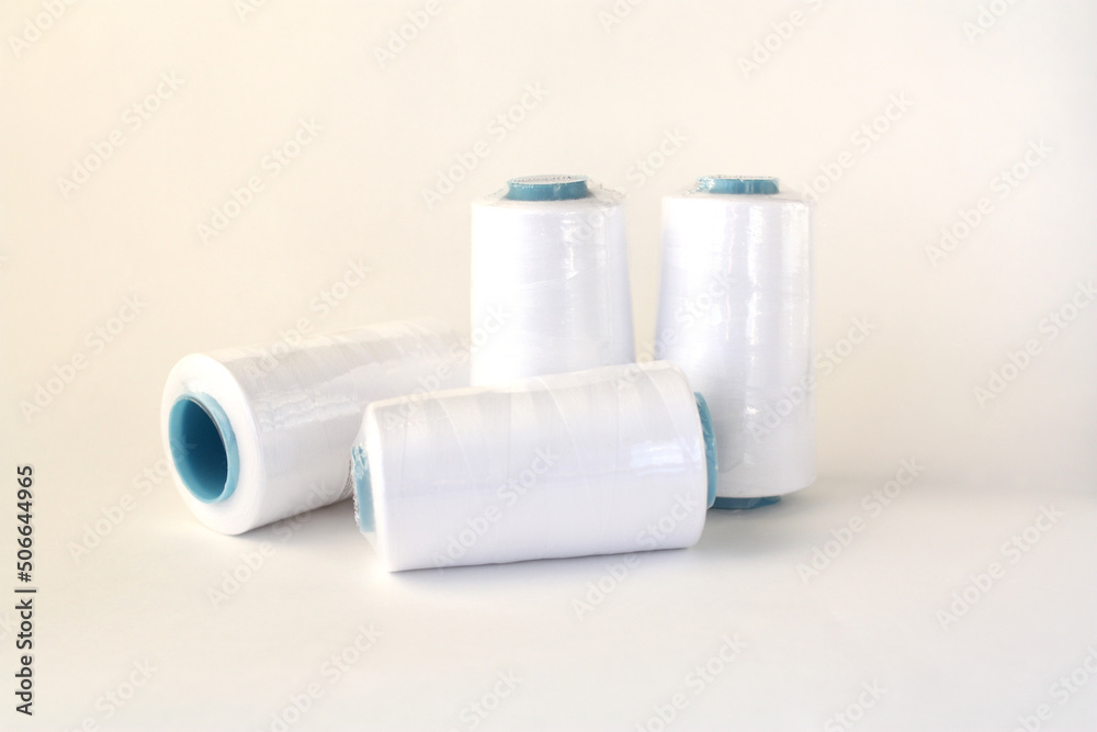 New white threads on a white background. Bobbins with threads for sewing in a package. New white threads on a white background. Bobbins with threads for sewing in a package.