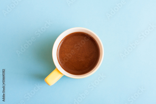A cup of hot coffee in pastel colors. Turkish coffee in a yellow mug on blue background.