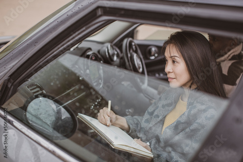 Woman with sketchpad drawing inside car photo