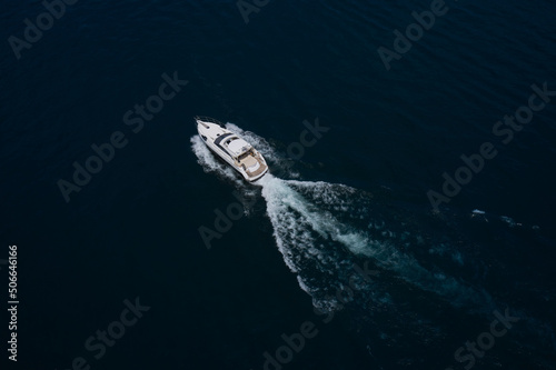 large yacht top view. Boats top white waves on dark water. Aerial view of a boat in motion in dark water. Large boat at high speed on dark blue water and top view.