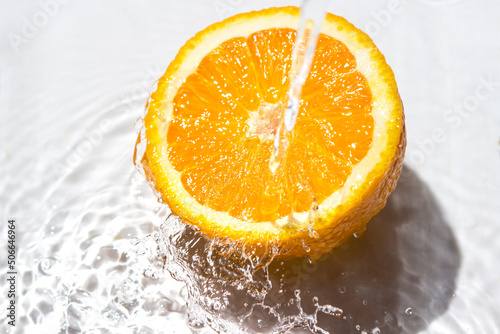 Fototapeta Naklejka Na Ścianę i Meble -  Water pours on an orange on a white background. Refreshing orange. Juicy fresh orange