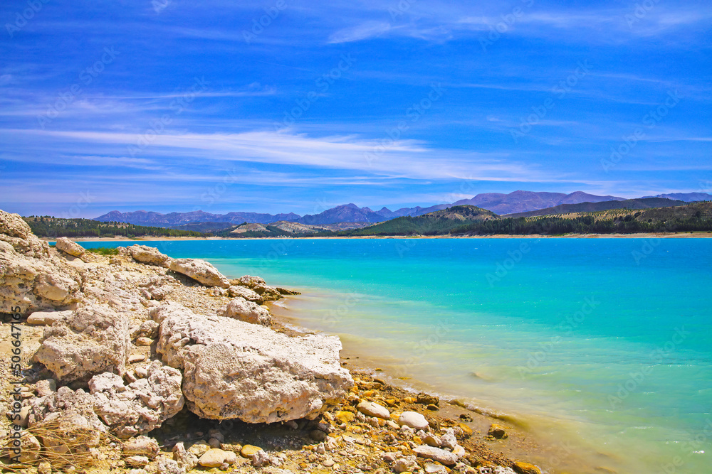 Beautiful calm blue turquoise mountain swimming lake, empty sand beach - Reservoir Vinuela, Malaga area
