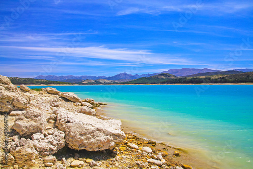 Beautiful calm blue turquoise mountain swimming lake, empty sand beach - Reservoir Vinuela, Malaga area