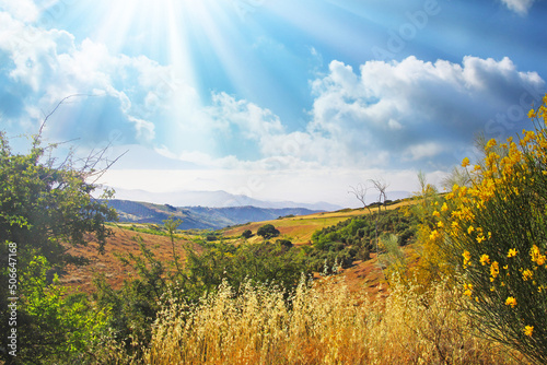 Beautiful quiet inspirational spanish morning mountain valley scene, sun rays, yellow genista broom shrub, agricultural fields, clouds sun rays - Spain, Andalusia