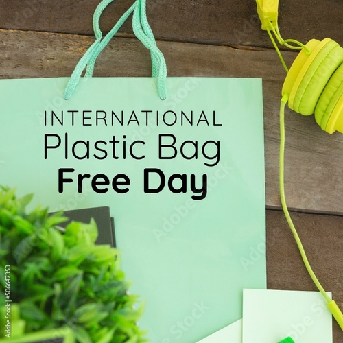 Overhead view of international plastic bag free day text on green paper bag at table