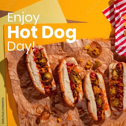 Composite of enjoy hot dog day text over hot dogs on brown paper, copy space