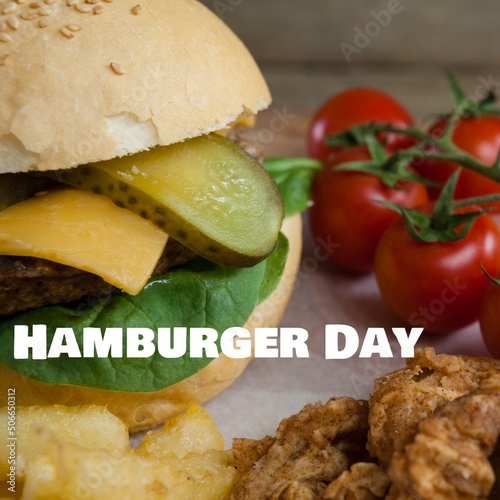 Close-up of hamburger day text with burger and tomatoes in plate, copy space