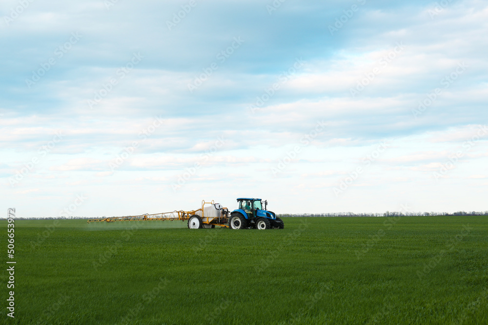 Tractor spraying pesticide in field on spring day. Agricultural industry Tractor spraying pesticide in field on spring day. Agricultural industry