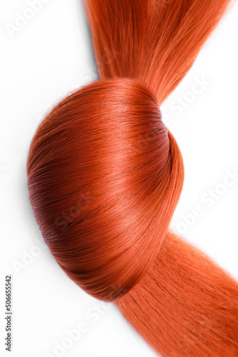 Beautiful strand of red hair tied in knot on white background  top view