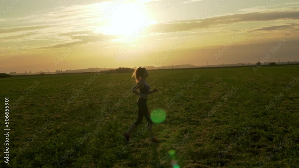 Girl Runs across Field at Sunset in Summer, Side View. Runner Jogging in Park at Sunset, Silhouette. Healthy Sports Lifestyle. Girl Runs across Field at Sunset in Summer, Side View. Runner Jogging in Park at Sunset, Silhouette. Healthy Sports Lifestyle.