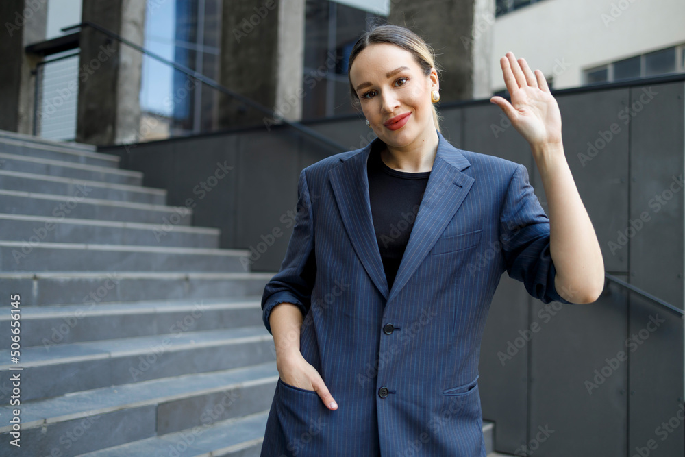Business woman waving hand stand on the background of a modern building Business woman waving hand stand on the background of a modern building