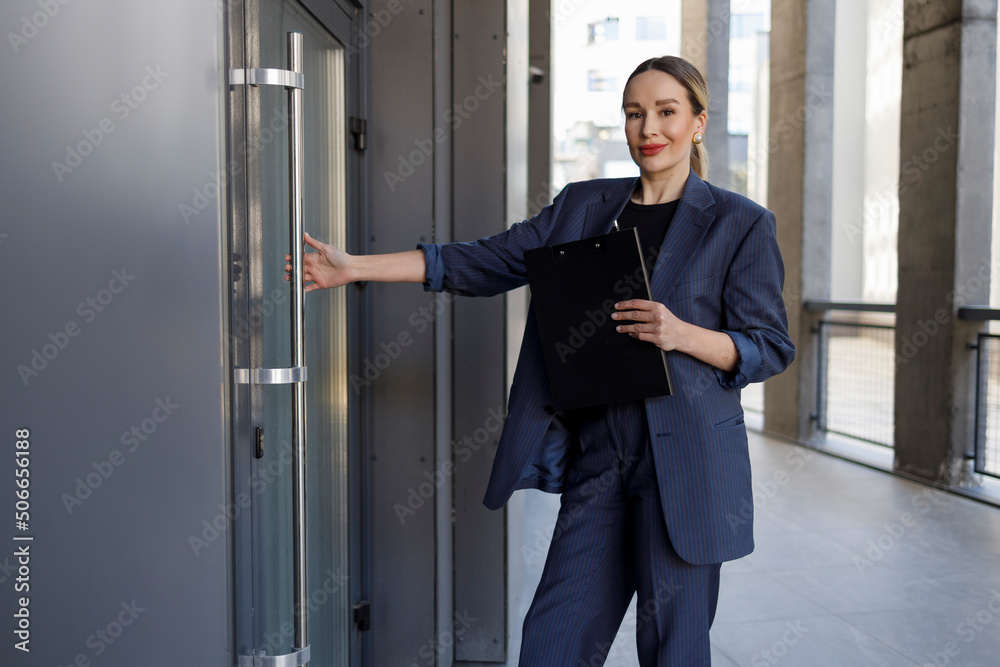 Fototapeta premium Elegant businesswoman with clipboard opening office door
