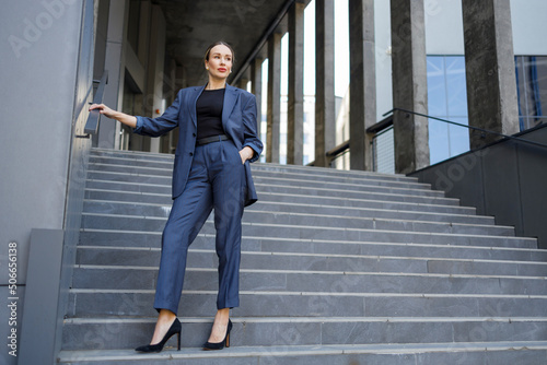 Stylishly dressed woman posing on the stairs of a modern building