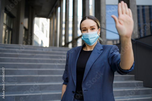 Pretty business woman in protective mask showing stop gesture