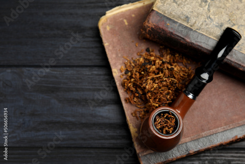 Smoking pipe, dry tobacco and old books on wooden table, top view. Space for text