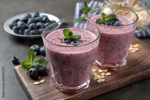 Glasses of tasty blueberry smoothie with oatmeal on dark grey table