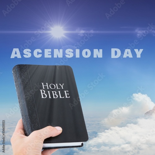 Ascension day text with hand of caucasian man holding bible against sunny sky, copy space