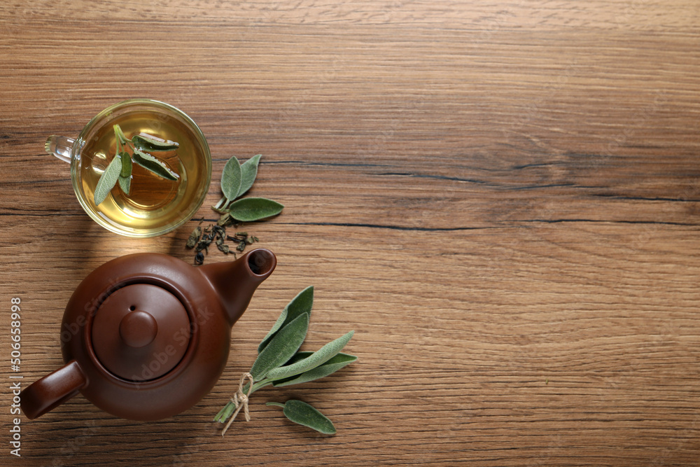 Cup of sage tea, green leaves and teapot on wooden table, flat lay. Space for text Cup of sage tea, green leaves and teapot on wooden table, flat lay. Space for text