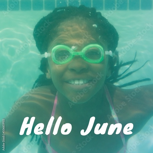 Potrait of smiling african ameican girl swimming underwater in pool with hello june text photo