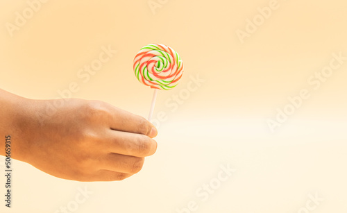 lollipop in a hand isolated on colorful background, front view