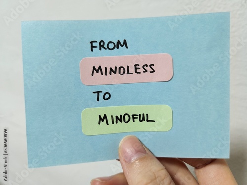 Hand holding a note showing the words From Mindless To Mindful  photo