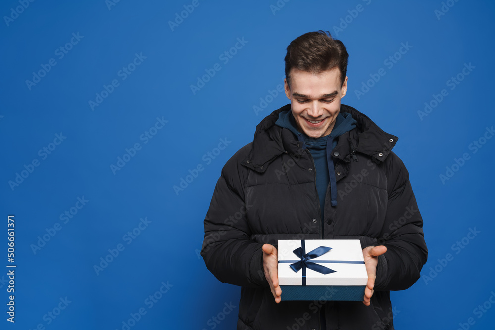 Young white man smiling while posing with gift box Young white man smiling while posing with gift box
