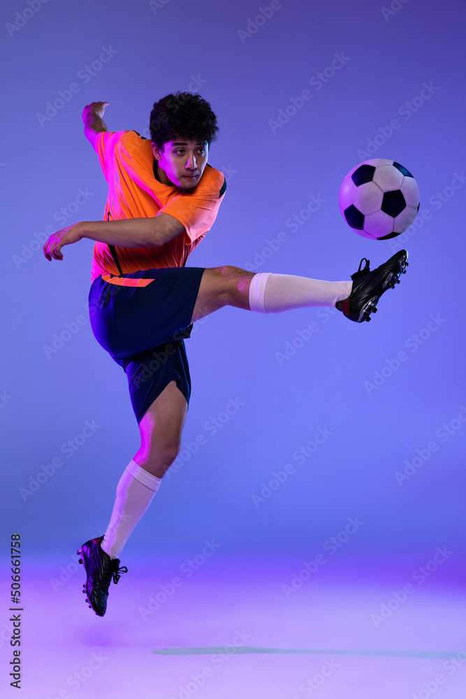 Studio shot of male professional football, soccer player practicing with ball isolated on purple background. Concept of sport, match, active lifestyle, goal and hobby Studio shot of male professional football, soccer player practicing with ball isolated on purple background. Concept of sport, match, active lifestyle, goal and hobby