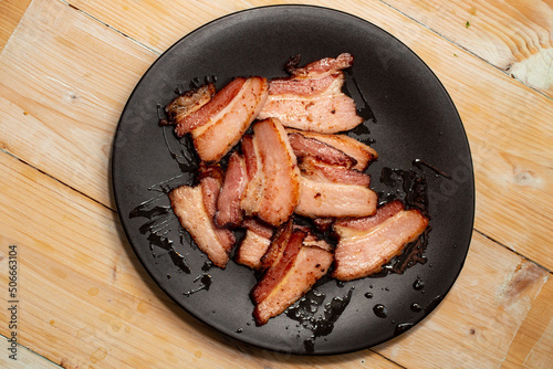 Thin sliced fried pork meat on a black ceramic plate