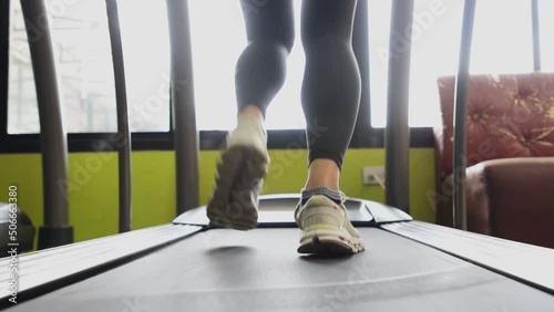 Young sports woman is working out in gym. Doing cardio training on treadmill.