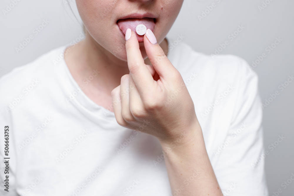 a woman with a pill on her tongue. close-up. medicine a woman with a pill on her tongue. close-up. medicine