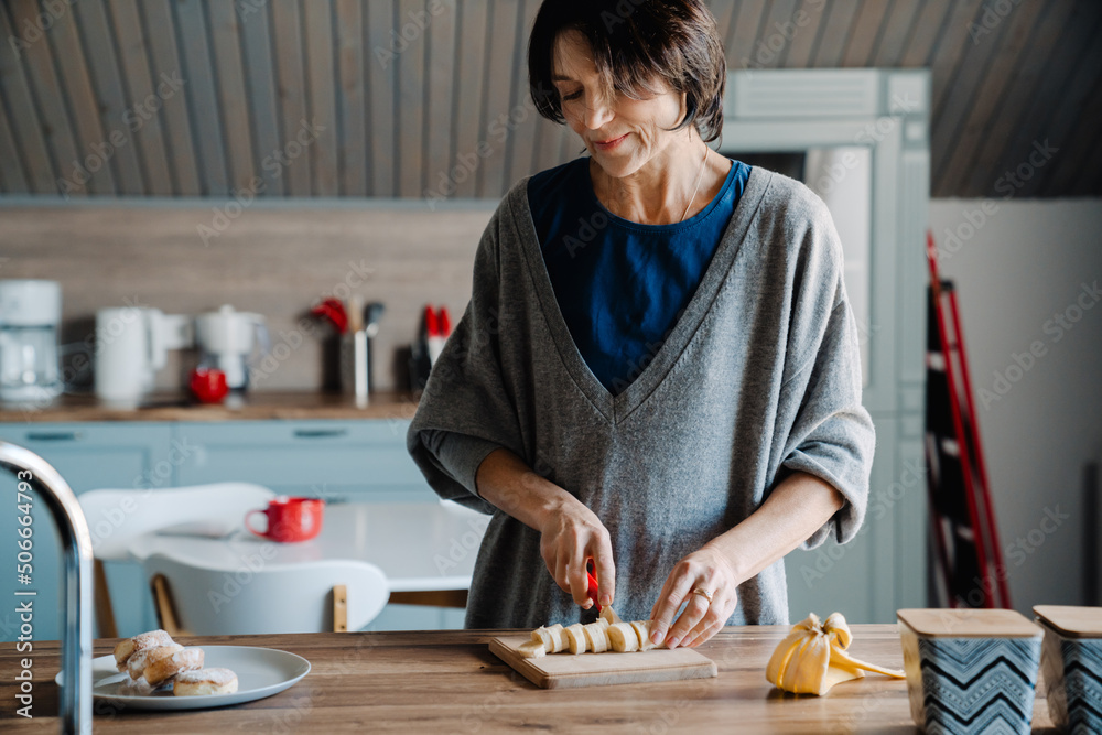 White mature woman smiling while making breakfast in kitchen White mature woman smiling while making breakfast in kitchen
