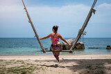 Mujer turísta disfrutando de bella playa, en columpio atado a palmeras