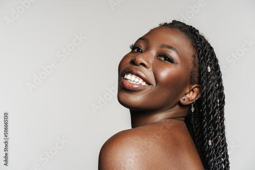 Shirtless black woman with afro pigtails smiling and looking at camera