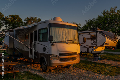 Class A and fifth wheel motorhomes parked next to each other at campsite