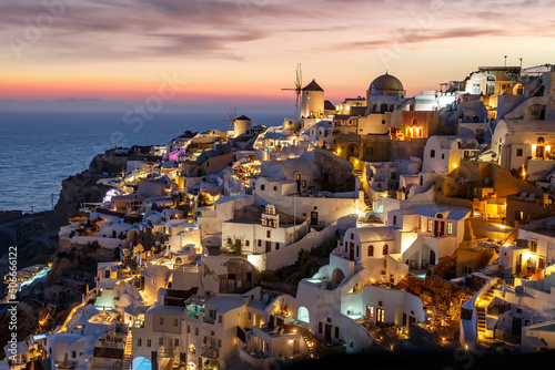 Santorini famous view with white houses and windmill during sunset. Vacation in Greece on the Aegean sea.