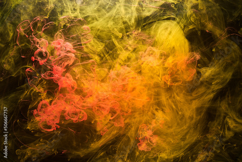 Yellow smoke on black background, colorful fog, abstract swirling ink ocean sea, acrylic paint pigment underwater
