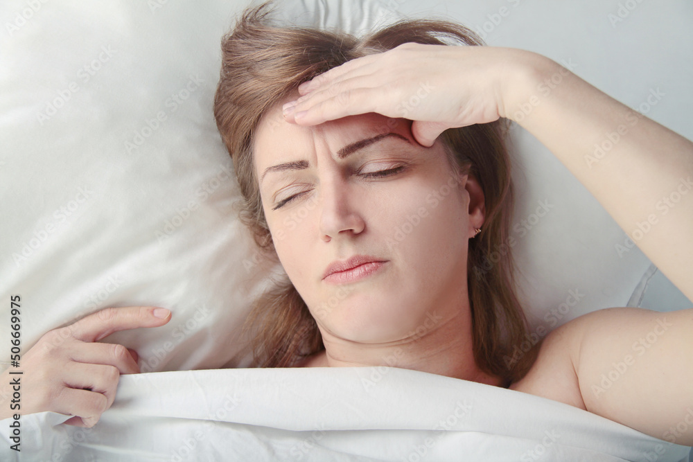 Foto de Disturbed annoyed young woman lying awake in bed