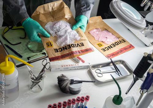 Police scientist holds evidence bag with underwear of sexual assault victim in crime lab, concept image