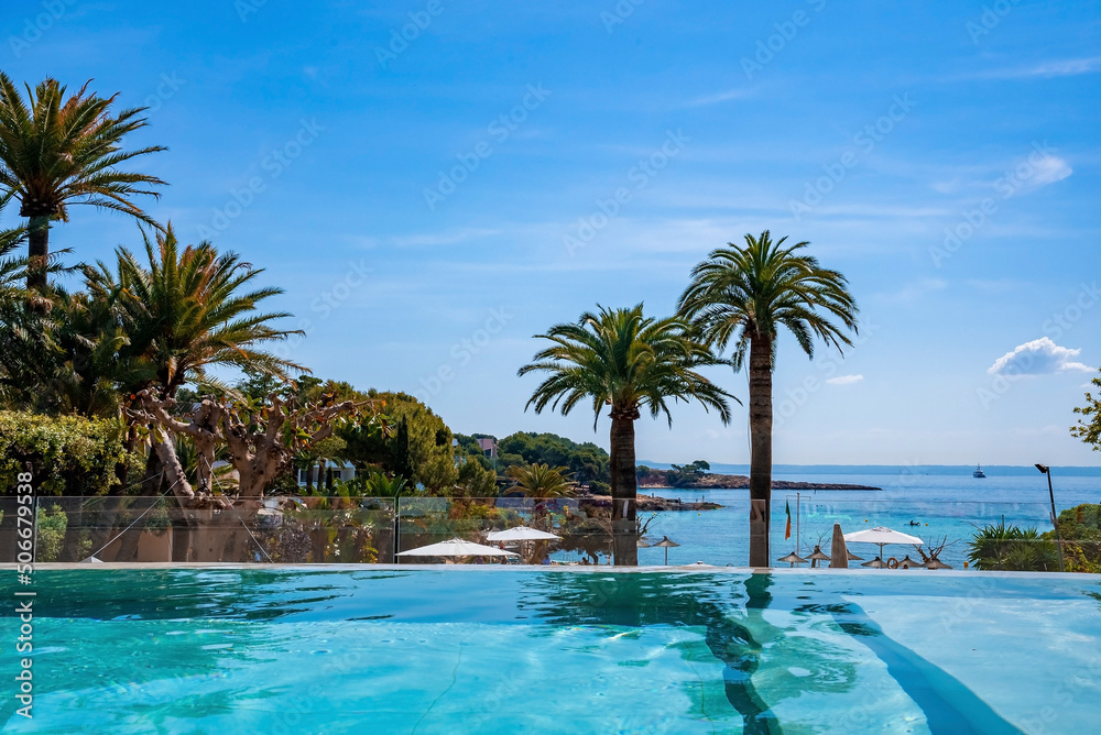 Swimming pool with view of trees and seascape. Scenic view of ocean against blue sky. Hotel spa on Mediterranean seaside during summer.