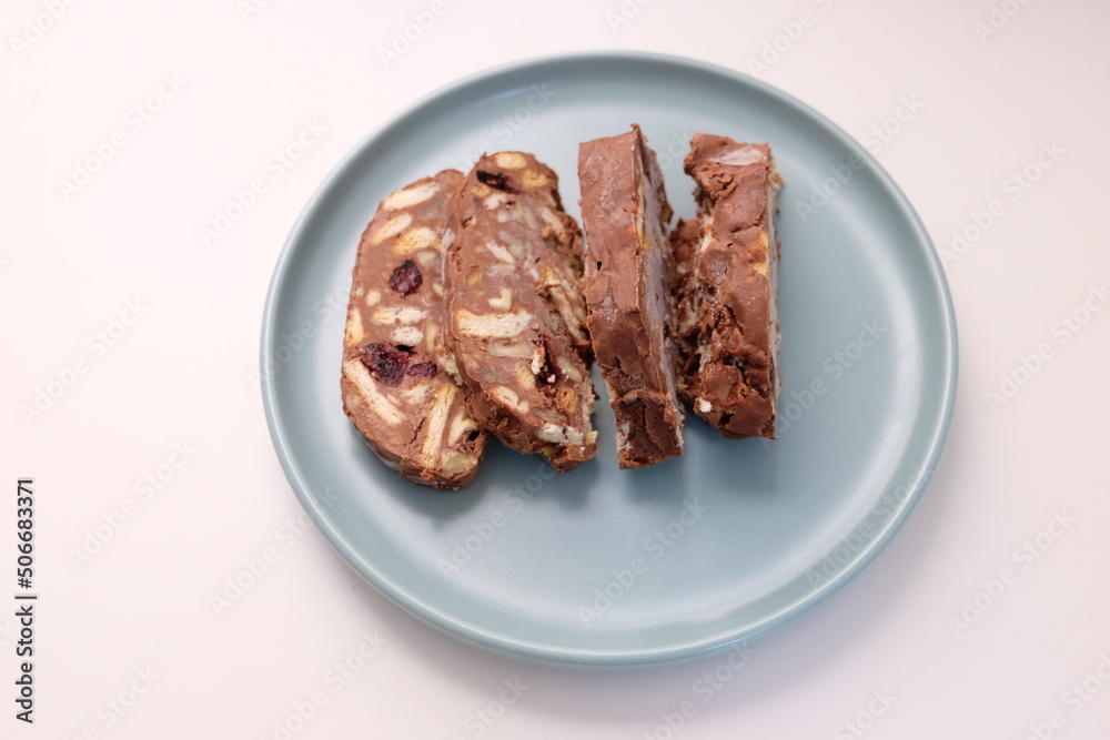 Homemade mosaic chocolate biscuit cake served in a blue plate, selective focus. It is called Homemade mosaic chocolate biscuit cake served in a blue plate, selective focus. It is called