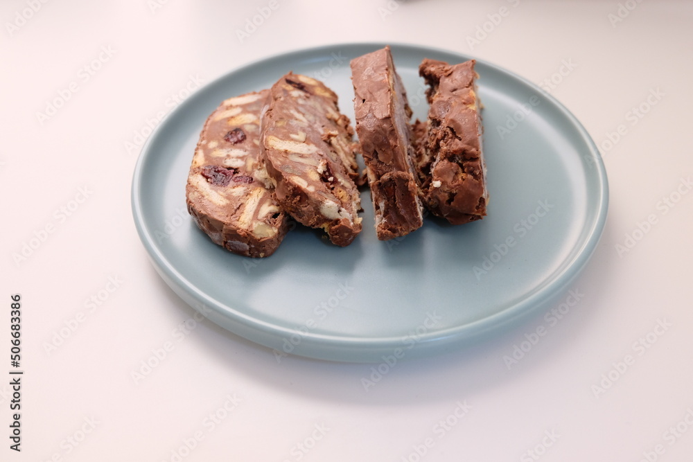 Homemade mosaic chocolate biscuit cake served in a blue plate, selective focus. It is called Homemade mosaic chocolate biscuit cake served in a blue plate, selective focus. It is called