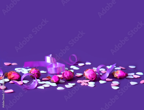 Festive concept from rosebuds and sweet hearts on purple background. Template mock up of greeting card or text design. Close-up