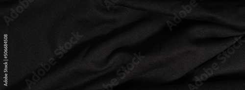 Black fabric background. Black wavy fabric in the dark