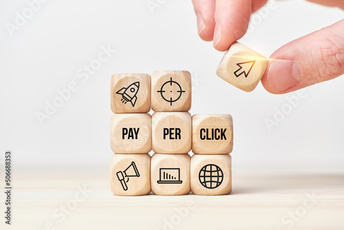 Concept Pay per click or PPC. Person stacks wooden cubes from text and icons.