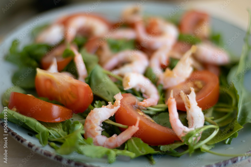 Shrimp salad with tomatoes, lettuce, arugula, avocado, cucumber and lemon dressing on blue table. Healthy eating, clean food concept. Top view