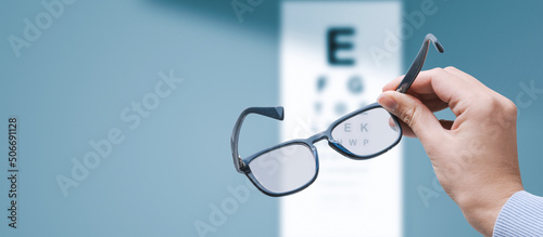 Optometrist holding glasses and eye chart photo