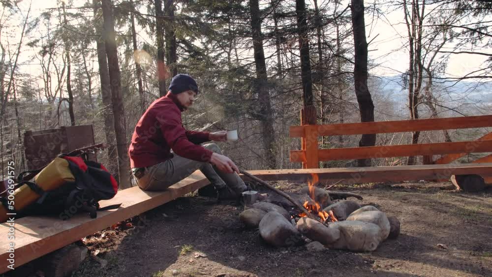 man sitting on chair near the camp with talking and drinking a cup of coffee. man sitting on chair near the camp with talking and drinking a cup of coffee.